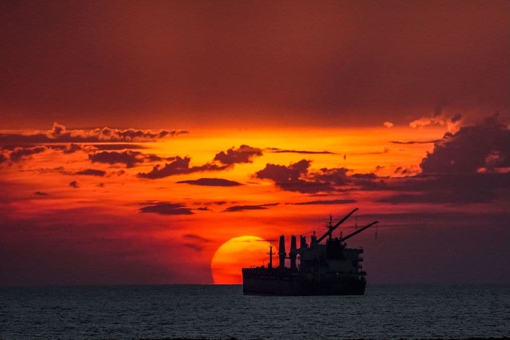 Sunset over the Pacific off Puerto Sandino, Nicaragua, with a cargo ship silhouetted against the sun